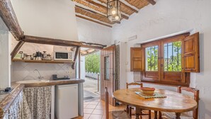Una cocina con mesa y sillas de madera, un microondas y un lavamanos.