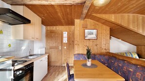 Un interior de madera con cocina, comedor y un banco.