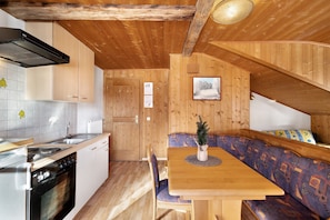 Interior em madeira com cozinha, área de jantar e um banco.