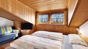 Una habitación de cabaña de madera con una cama, un sofá y un televisor.