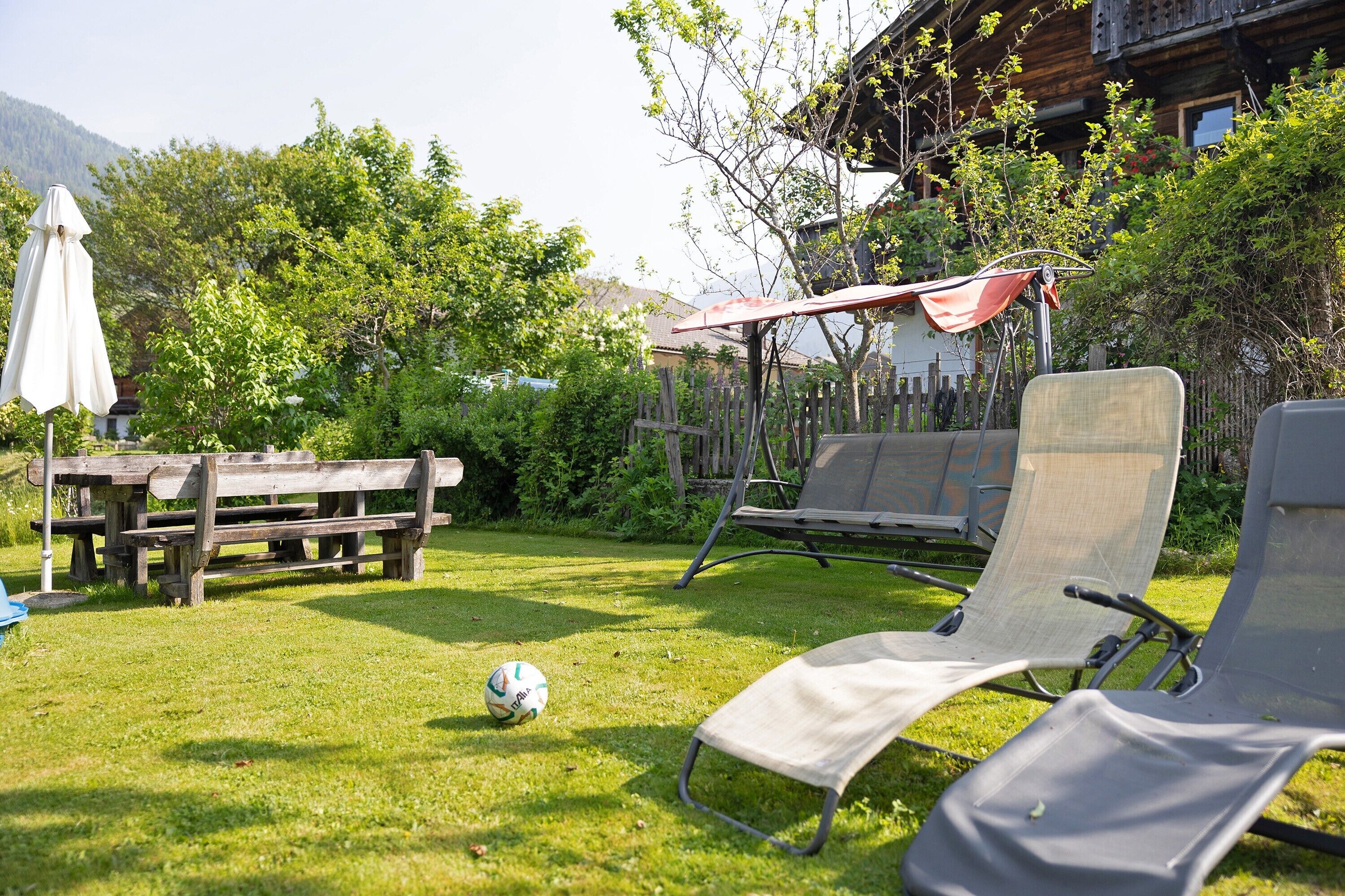 Un espace extérieur verdoyant avec une table de pique-nique, deux chaises longues et un ballon de football.