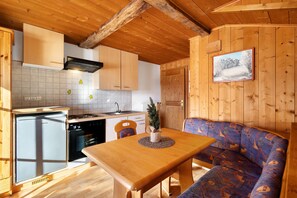 A wooden interior with a kitchen, dining area, and a sofa.
