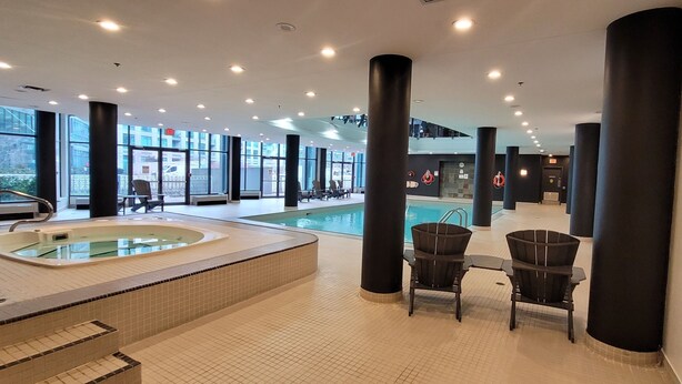 A modern indoor swimming pool area with a hot tub, lounge chairs, and large windows. - Studio for 2 in Downtown Toronto  (Toronto)