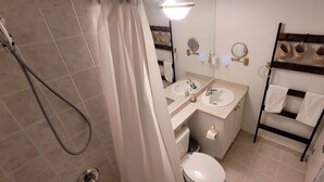 A bathroom with a shower, two sinks, a toilet, and a towel rack with multiple towels. - Studio for 2 in Downtown Toronto  (Toronto)