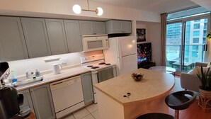 A modern kitchen with grey cabinets, a microwave, stove, and a dining area with a round table and chairs. - Studio for 2 in Downtown Toronto  (Toronto)