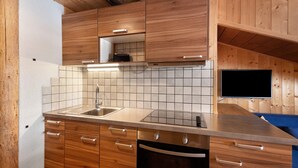 Una cocina moderna con armarios de madera, un lavamanos de acero inoxidable y un televisor integrado.
