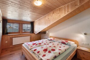 A wooden-paneled room with a bed, a nightstand, a window with a view, and a ceiling light.