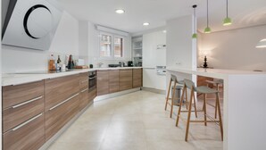 A modern kitchen with wooden cabinets, a built-in oven, a window, and a bar area with stools.