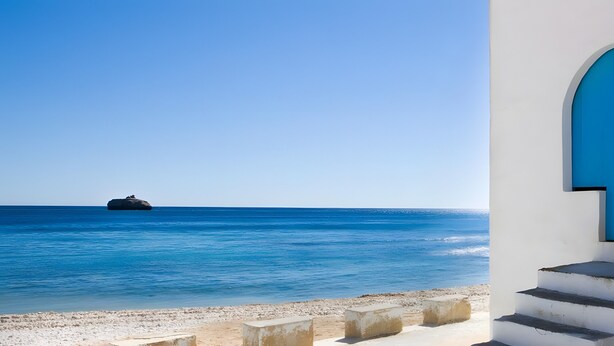 A coastal view with a blue door and steps leading to a white building.