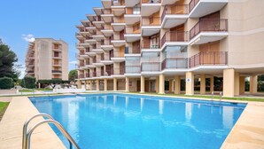 A swimming pool with a metal ladder, surrounded by multi-story buildings with balconies.