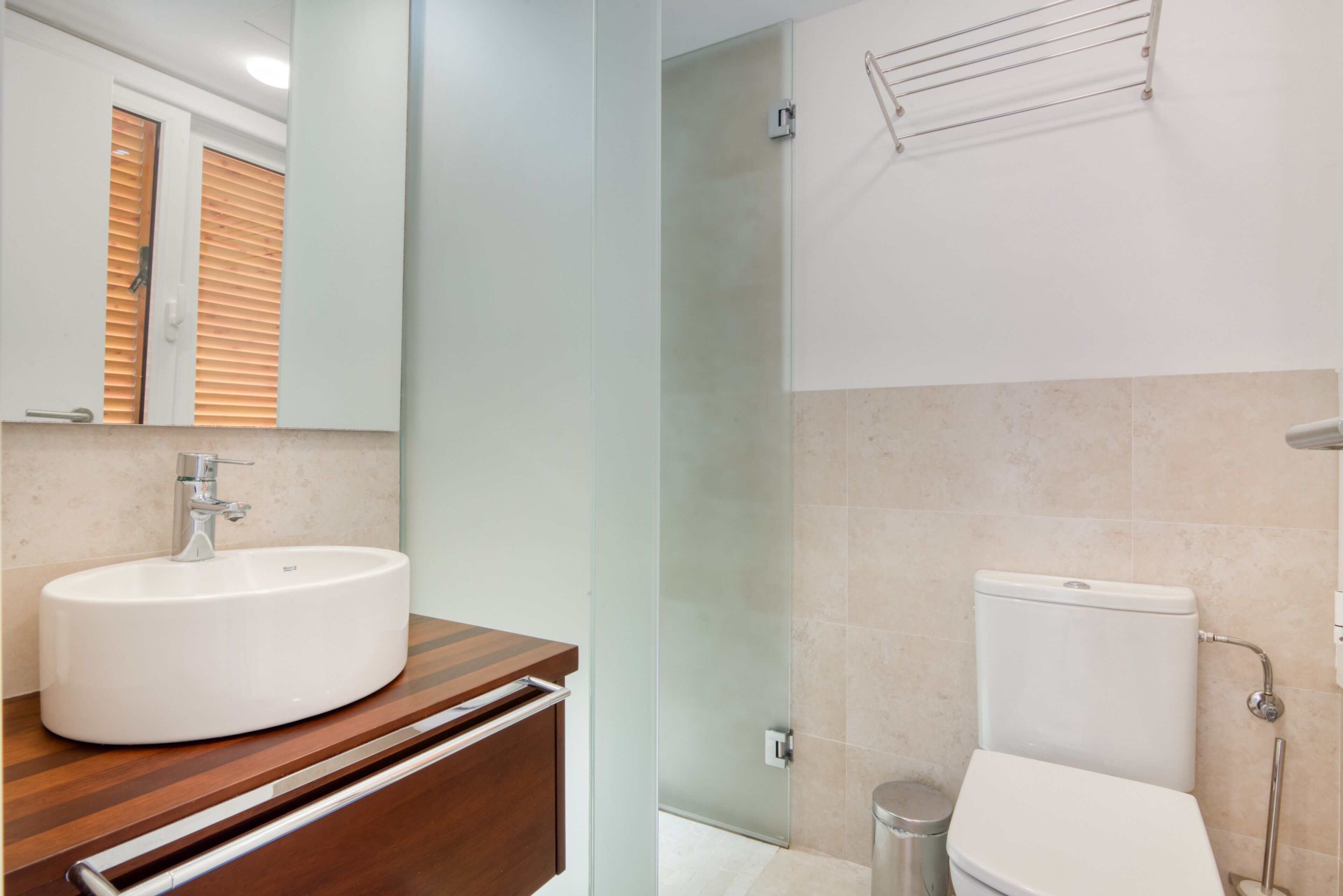 A bathroom with a sink, mirror, toilet, and shower.