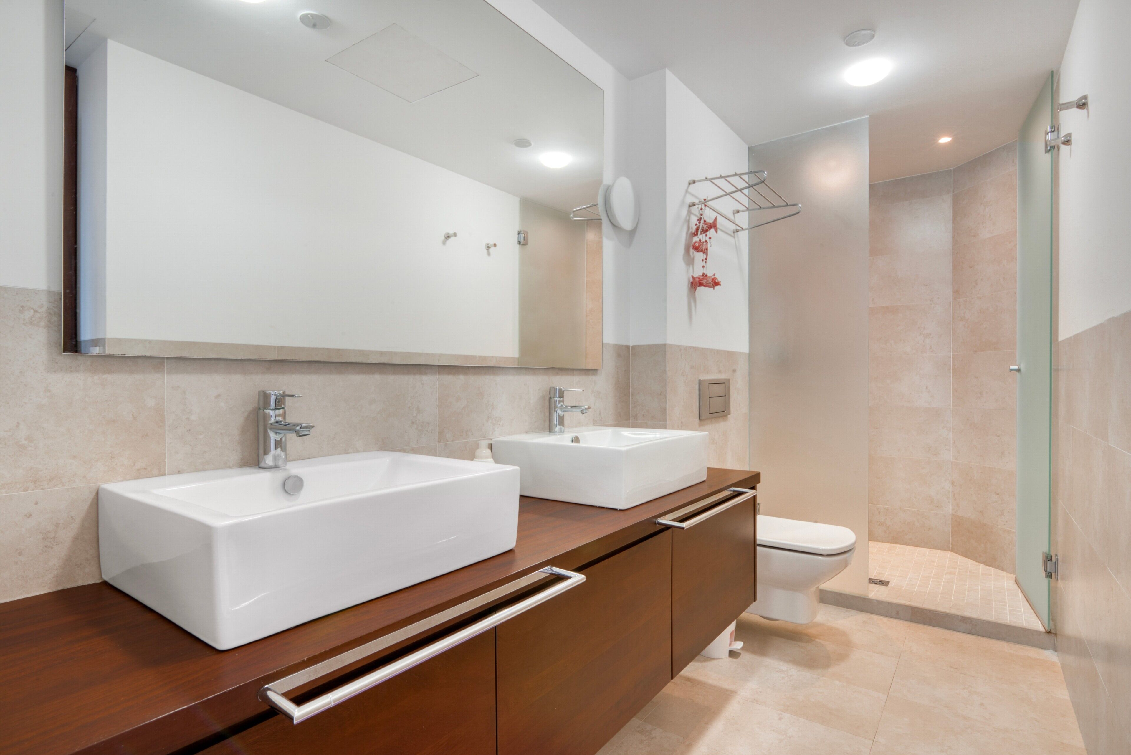 Une salle de bain moderne avec deux lavabos, un miroir et une douche.