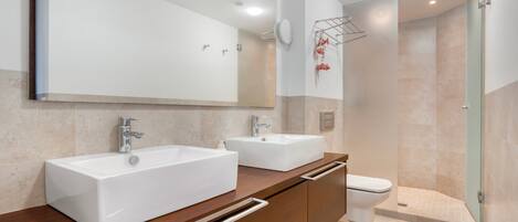 Une salle de bain moderne avec deux lavabos, un miroir et une douche.