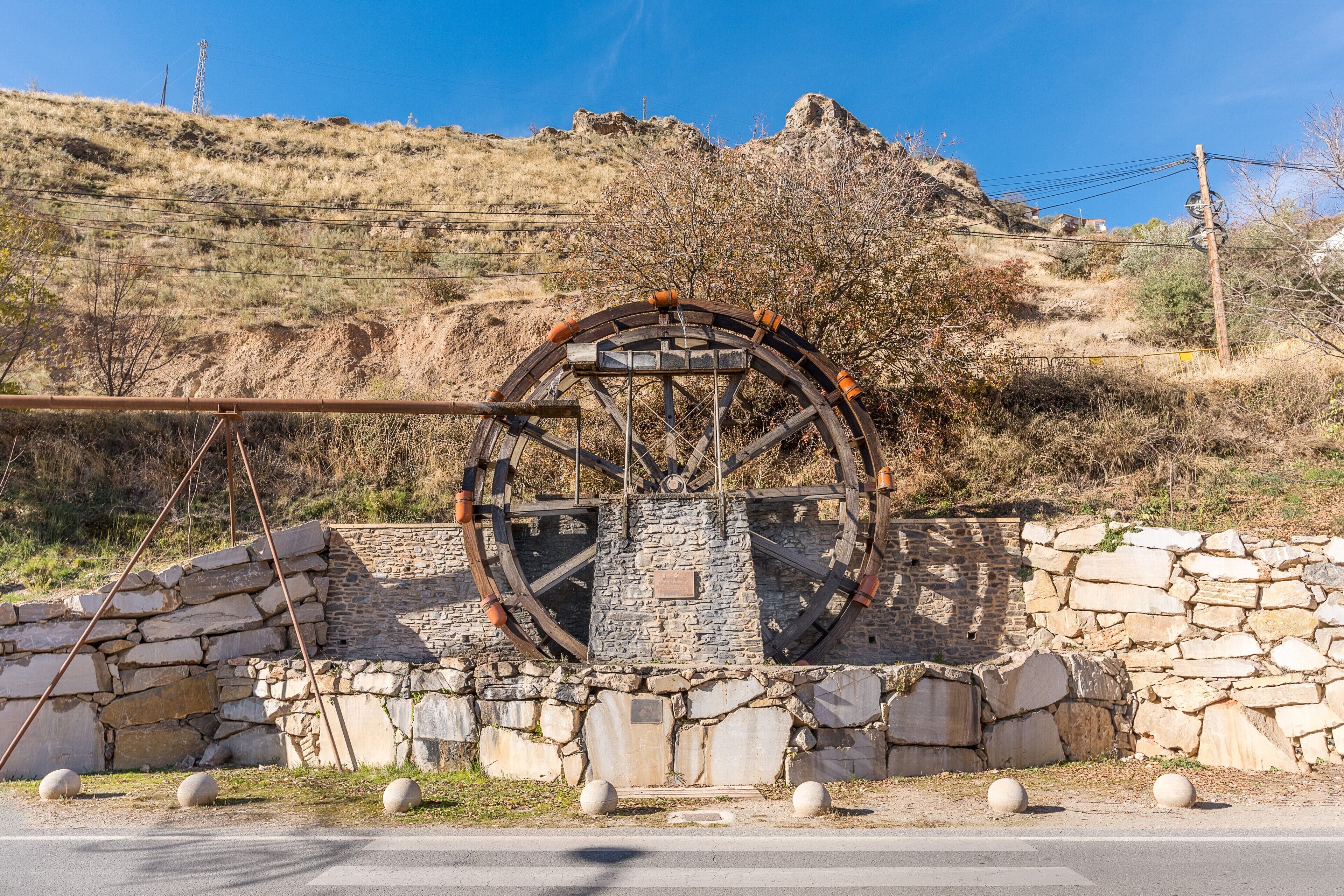 A historical water wheel structure with stone walls and a clear sky.