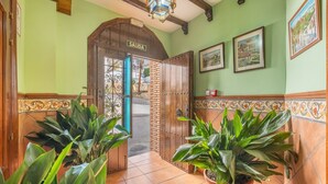 A hallway with a wooden door labeled 'SALIDA,' potted plants, tiled flooring, and framed pictures on the wall. - Apartment 'Apartamento De 1 A 2 Personas' with Balcony and Wi-Fi (Güejar Sierra)