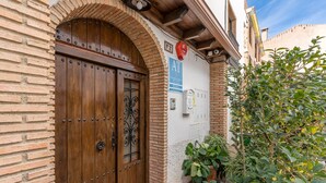 A brick building with a wooden double door, a red mailbox, and a sign indicating a rural location. - Apartment 'Apartamento De 1 A 2 Personas' with Balcony and Wi-Fi (Güejar Sierra)