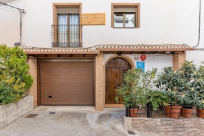 A building with a closed wooden garage door, a small balcony with a metal railing, and a sign above the door.