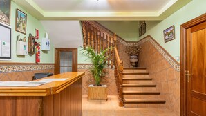 A reception area with a wooden counter, a staircase with a wooden railing, and a potted plant. - Apartment 'Apartamento B' with Private Terrace and Wi-Fi (Güejar Sierra)