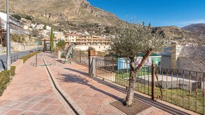 A paved walkway with a metal fence, a street lamp, and a view of a hillside with buildings. - Apartment 'Apartamento B' with Private Terrace and Wi-Fi (Güejar Sierra)