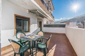 A patio with a table and chairs, a window, and a view of mountains.