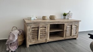 Une console en bois rustique, agrémentée de paniers tressés, d’une boîte à mouchoirs et d’une petite plante en pot.