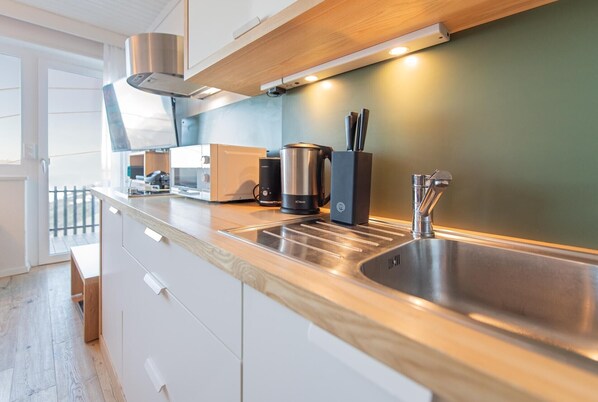 A modern kitchen with a stainless steel sink, a coffee maker, and a kettle.