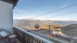 Ein Balkon mit Korbstühlen, einer Seilbahn und Blick auf die Berge.