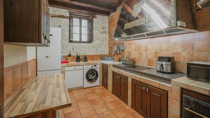 A kitchen with wooden cabinets, a washing machine, a microwave, and a stove.