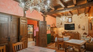 A dining area with wooden furniture, a chandelier, and a television on the wall.
