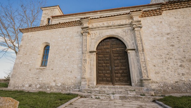 A stone building with a large wooden door and a small window.