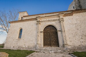 A stone building with a large wooden door and a small window.