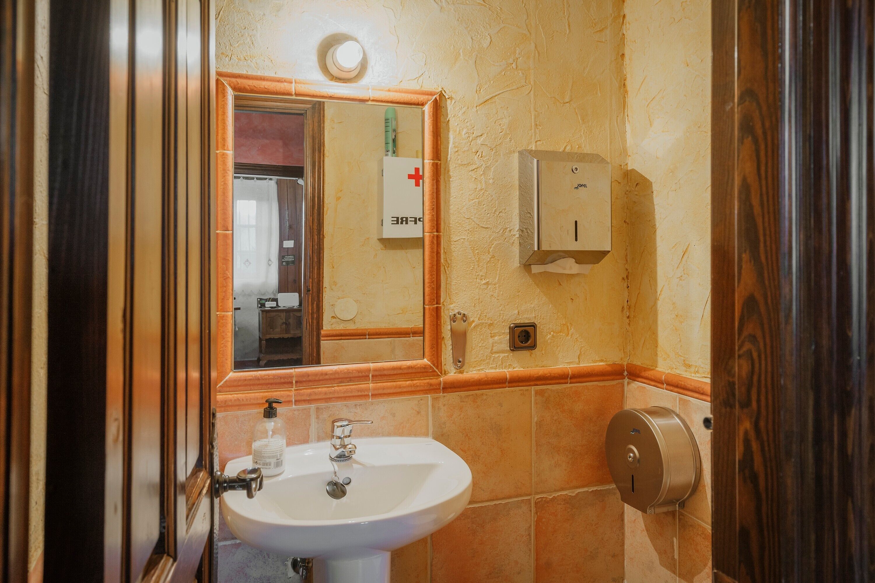 Een badkamer met een wastafel, spiegel en handdroger.