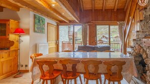 Une table à manger en bois, quatre chaises, une lampe rouge et un tableau accroché au mur.