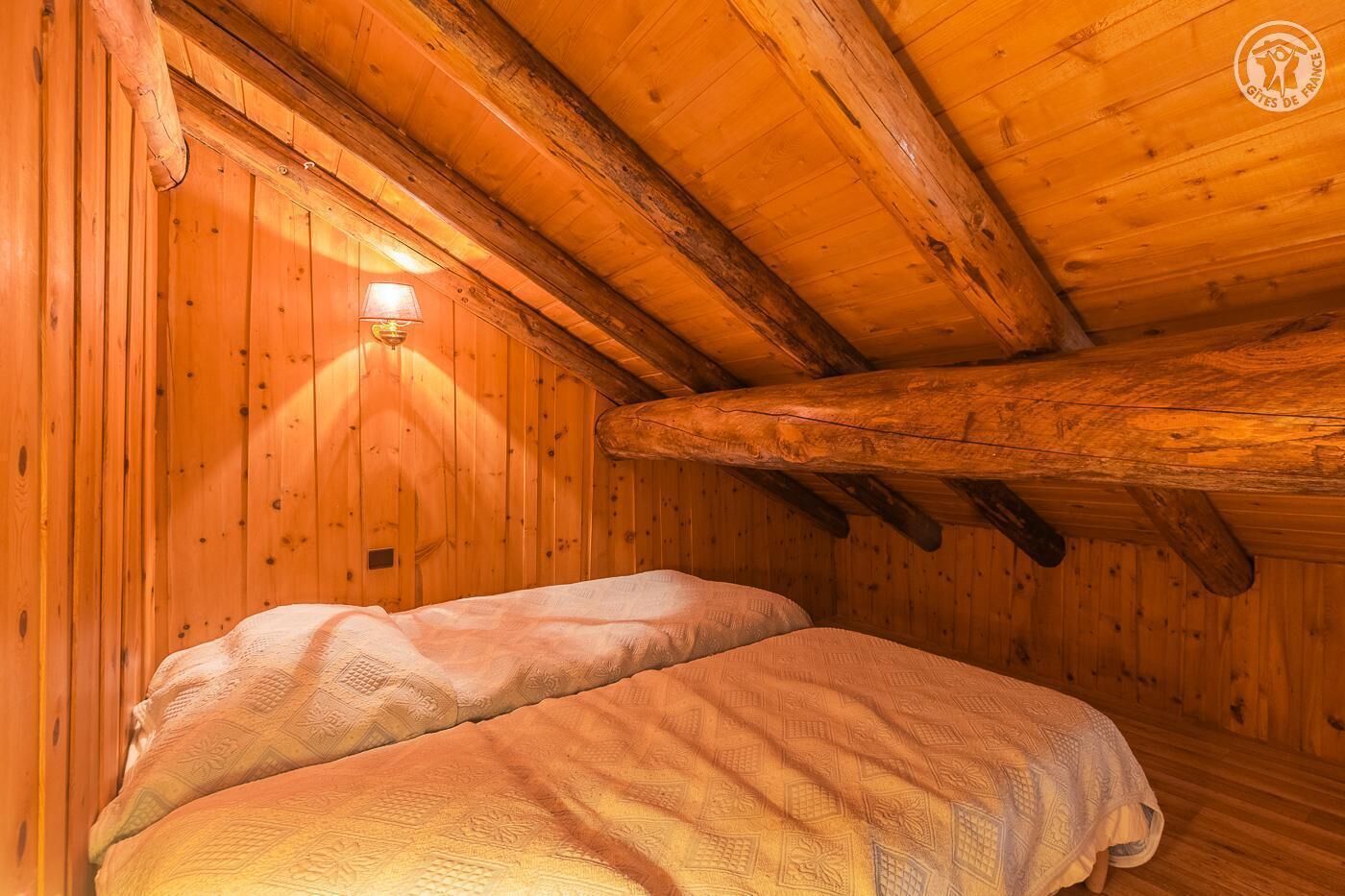 Ett mysigt rum i en stuga, inrett med träpanel, med en säng och en vägglampa.