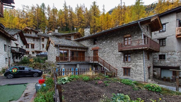 Un bâtiment traditionnel en pierre, doté de balcons, avec une voiture garée devant.