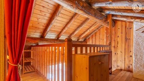 L’intérieur d’une cabane en bois, avec un plafond en pente, des murs en bois et un rideau rouge.