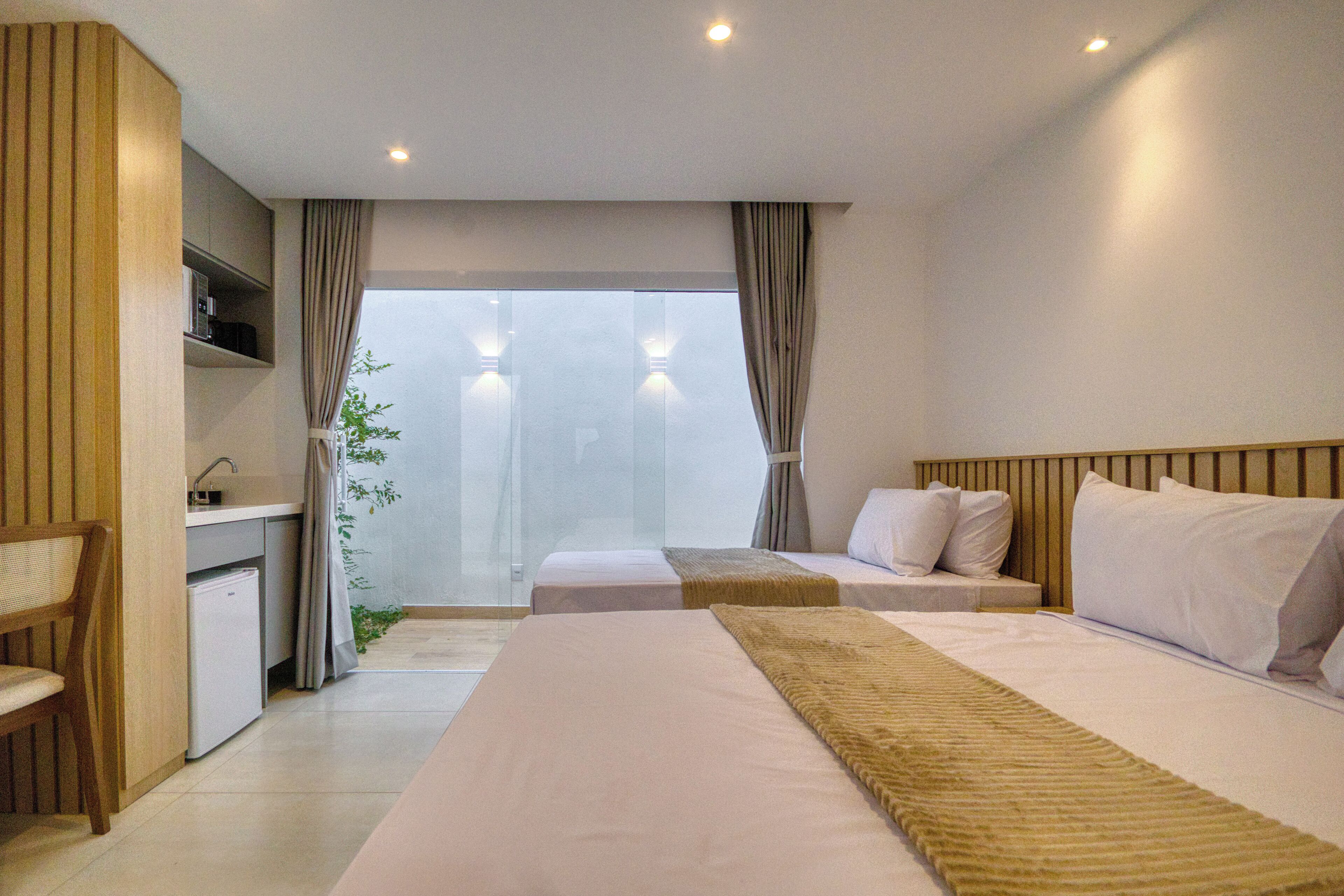 Habitación de hotel con una cama grande, una cama más pequeña, un escritorio y vistas al exterior.