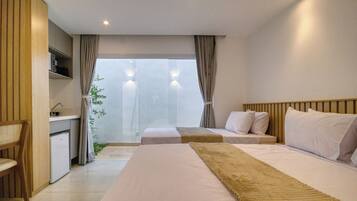 Habitación de hotel con una cama grande, una cama más pequeña, un escritorio y vistas al exterior.