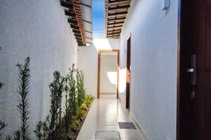 Un pasillo estrecho, iluminado por el sol, con techo de madera y una puerta al final.