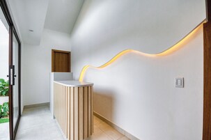 Un mostrador de recepción moderno con detalles de madera y una lámpara de pared de diseño curvo.