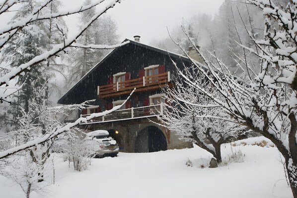 A log cabin with a stone foundation, wooden exterior, and a balcony with red railings.