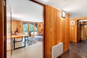 Een modern interieur met houten wanden, een eethoek met tafel en stoelen, en uitzicht door grote ramen.