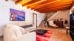 A living room with a sofa, coffee table, and a staircase leading to a loft.
