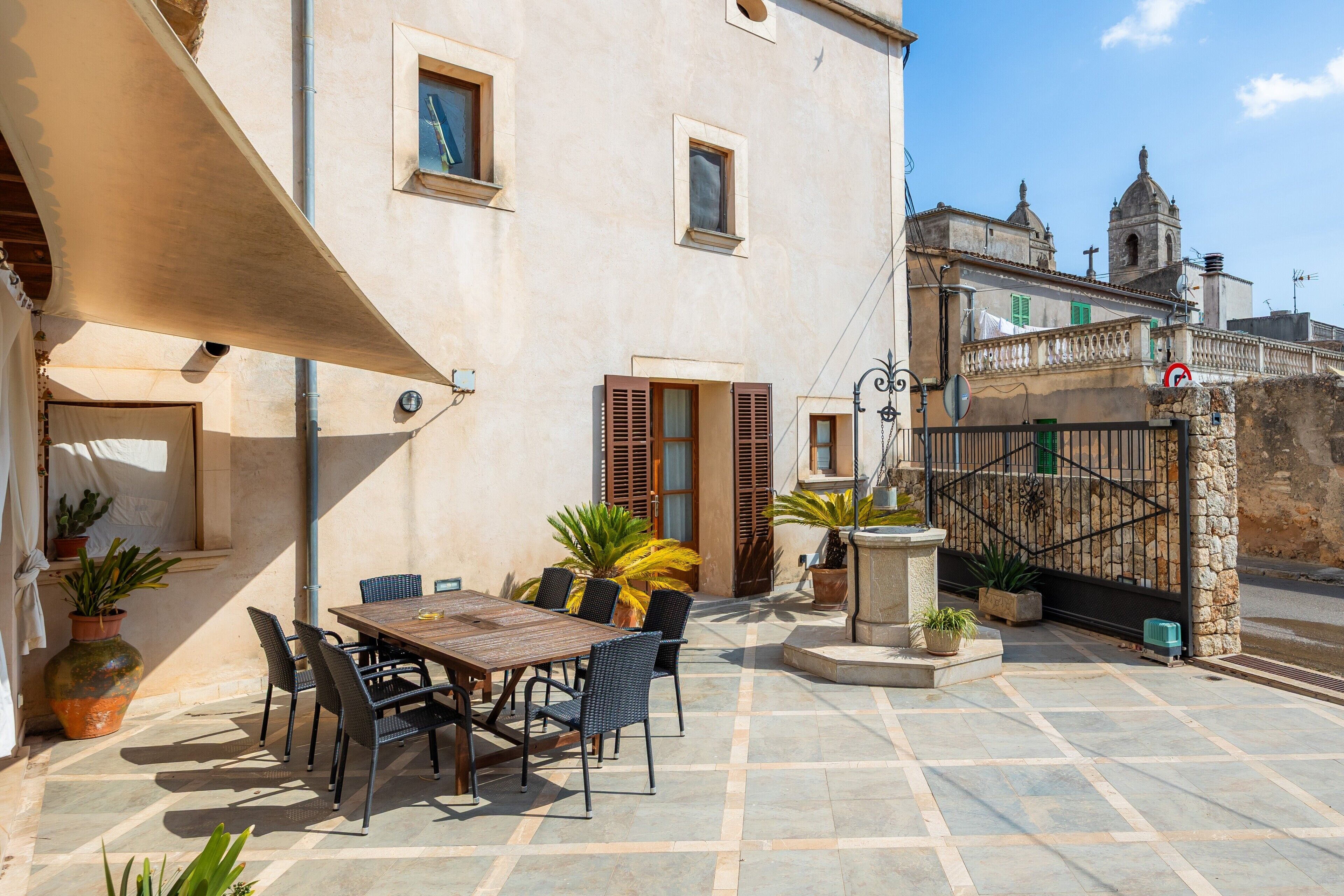 Un patio exterior con una mesa y sillas, plantas en macetas y vistas a un edificio histórico.