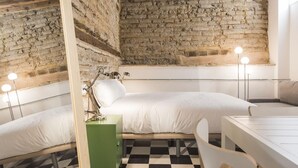 A room with a brick wall, a bed, a desk, and a chair.