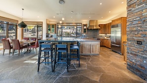 Una cocina moderna con una isla central, suelo de piedra y una pared decorativa de piedra.