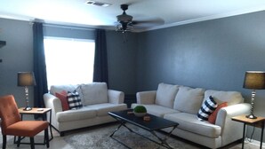 Ein Wohnzimmer mit einer Couch, einem Sessel, einem Couchtisch und zwei Lampen.
