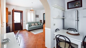 Een compacte leefruimte met een kitchenette, een eethoek en een bank in de woonkamer.