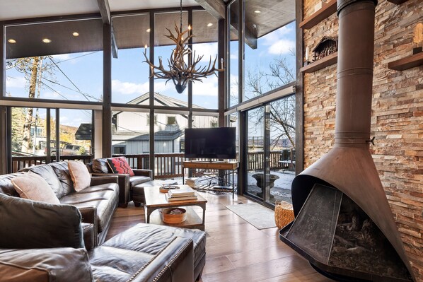 A spacious living room with a large fireplace, leather furniture, and a television.