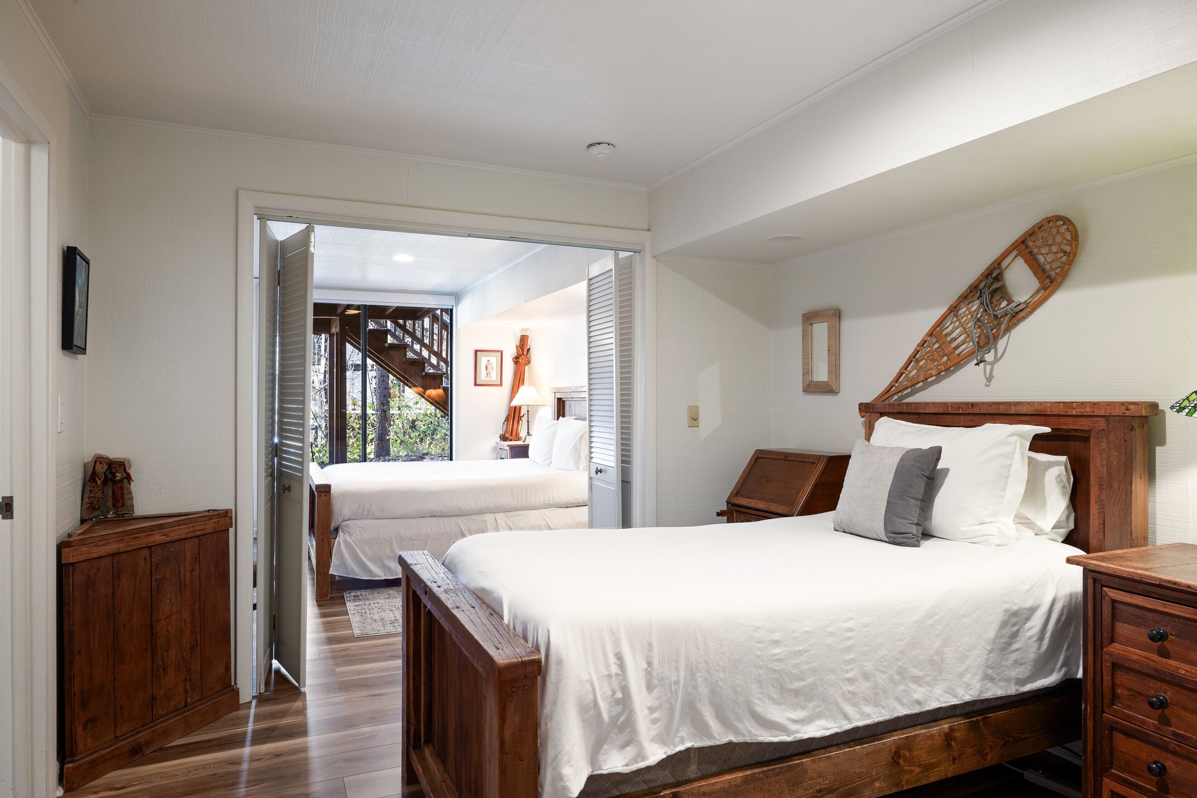 Une chambre avec deux lits, des têtes de lit en bois, une table de chevet en bois et une vue sur un balcon.